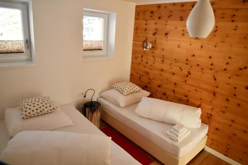 a bedroom with two beds and a wooden wall at Serpentin Apartment in Turracher Hohe