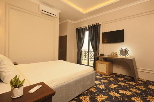 a hotel room with a bed and a desk and a television at Phước Hưng 3 Hotel in Vĩnh Long