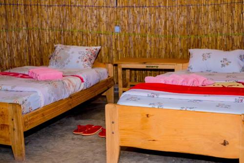 2 camas en una habitación con zapatillas en el suelo en Kitabi EcoCenter, en Gabegi