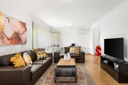 a living room with a couch and a tv at Close to Geelong 4 Bedroom home by Short & Long Stays in Belmont