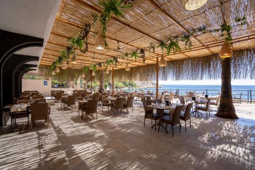 a restaurant with tables and chairs and the ocean at Hotel Mavi Deniz in Turunç