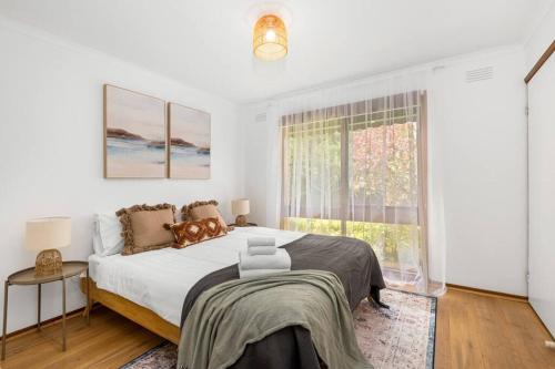 a white bedroom with a large bed and a window at Close to Geelong 4 Bedroom home by Short & Long Stays in Belmont
