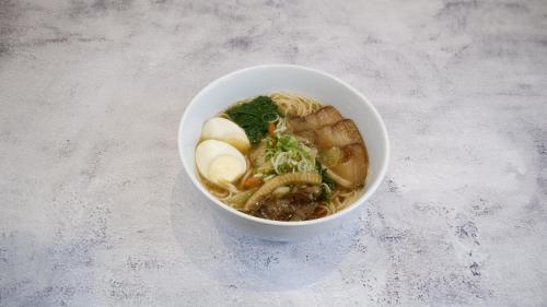 a bowl of soup with noodles and vegetables on a table at RELOhomes Serviced Apartment in Mumbai