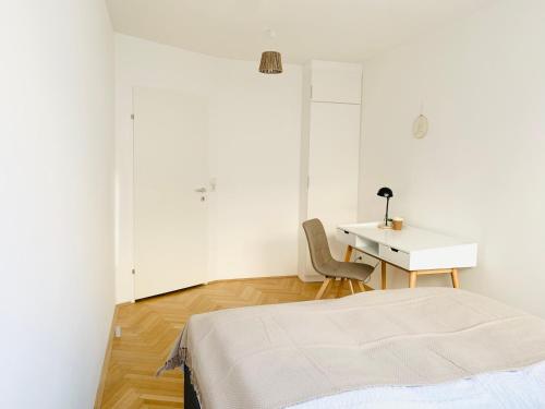 Jest to biały pokój z łóżkiem i biurkiem. w obiekcie Ruhige Wohnung im Gasometer Wien *WIFI*U3*Netflix* w Wiedniu