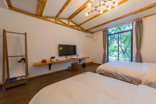 a bedroom with two beds and a tv and a mirror at Jiannanshan Garden Homestay in Kunming