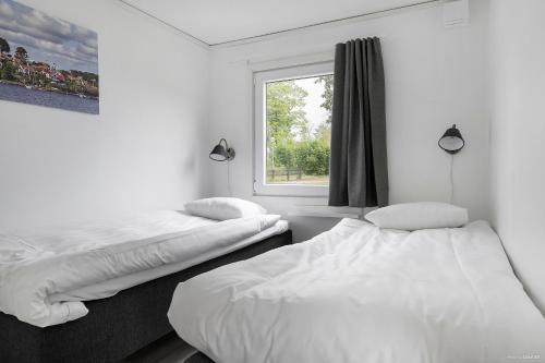 two beds in a room with a window at First Camp Skönstavik Karlskrona in Karlskrona