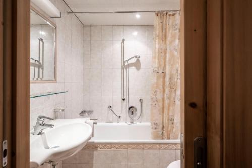 ein Bad mit einer Badewanne, einem Waschbecken und einer Dusche in der Unterkunft Garni Reider in Sexten