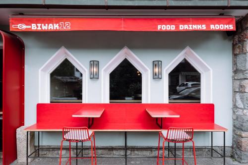 a red counter with three chairs in front of a food dining room at Garni Reider in Sesto