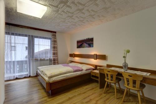 Un dormitorio con una cama, un escritorio y una mesa. en Appartements Hofer, en San Giacomo