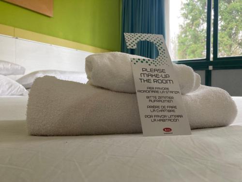 una pila de toallas sentadas encima de una cama con un cartel en Green Hotel Motel, en Vergiate