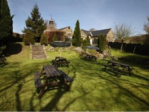 a group of picnic tables and an umbrella in a yard at The Plough Inn in Hathersage