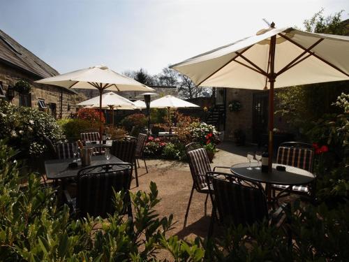 eine Gruppe von Tischen und Stühlen mit Sonnenschirmen in der Unterkunft The Plough Inn in Hathersage