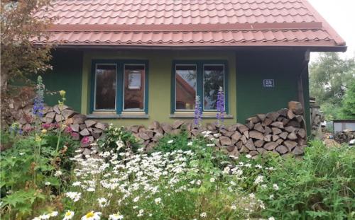 a green house with a rock wall in front of it at Zielony Domek w Sztynorcie in Sztynort