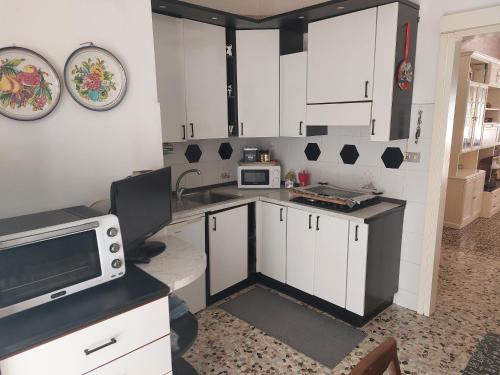 een kleine keuken met witte kasten en een magnetron bij Appartamento La Fortezza in Livorno