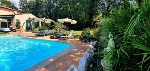 a swimming pool with two chairs and an umbrella at Les Bergeries in Tourrettes-sur-Loup
