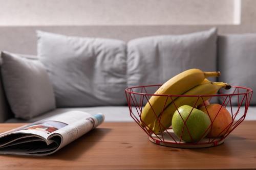 a basket of fruit on a table next to a book at Enattica Syntagma Living in Athens