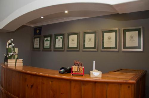 un comptoir en bois avec un téléphone et des certificats sur le mur dans l'établissement Del Roza Guest House, à Middelburg