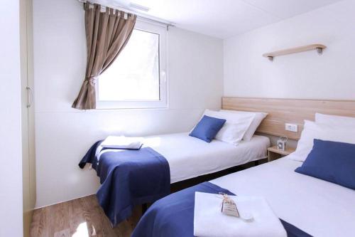 um quarto de hotel com duas camas e uma janela em Mobile homes in Camp Soline at Biograd, with sand- and pebble beach em Biograd na Moru