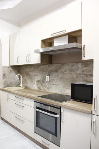 uma cozinha com armários brancos e um forno com placa de fogão em Margo em Yaremche