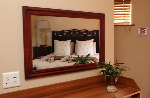 a mirror reflecting a bed in a bedroom at Del Roza Guest House in Middelburg