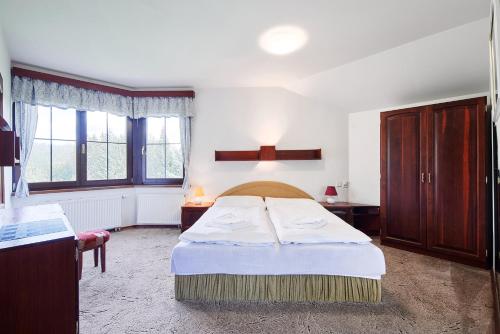 a bedroom with a bed and two windows at Chalupy Na Rališce in Horní Bečva