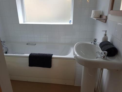 un bagno bianco con lavandino e vasca di Ty'n y Cwm, Nant Peris a Dinorwic