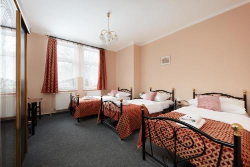 a room with four beds and a table and windows at Hotel Roosevelt in Litoměřice