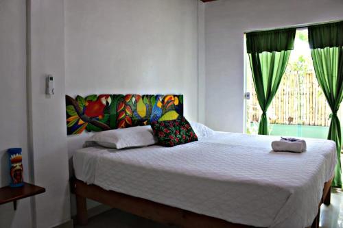 a bedroom with a bed with white sheets and a window at Hotel & Restaurante Siami in Leticia