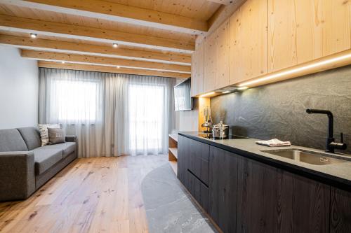 uma cozinha com um lavatório e um sofá num quarto em Bio Lüch Ruances em San Cassiano