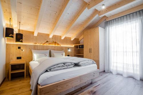 Un dormitorio con una cama grande en una habitación con techos de madera. en Bio Lüch Ruances en San Cassiano