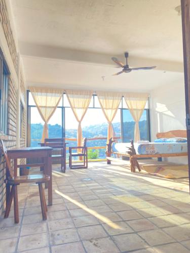 a room with benches and tables and windows at Casa Gundi y Tomas in Puerto Ángel