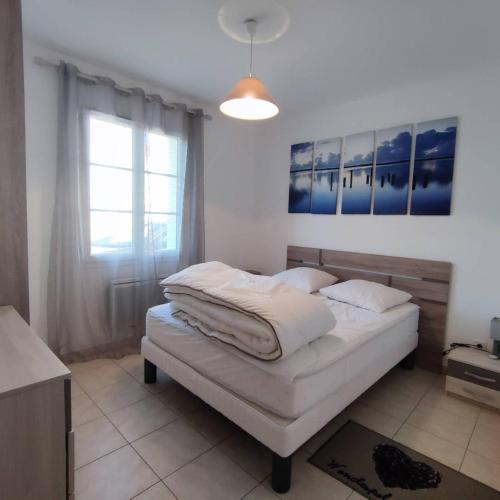 a bedroom with a bed with white sheets and a window at Avec piscine à Dolus in Dolus-d'Oléron