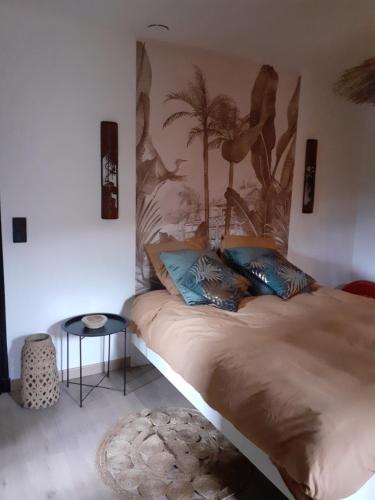 1 dormitorio con 1 cama con una pintura en la pared en Gîte privé avec sauna et balnéo, en Brens