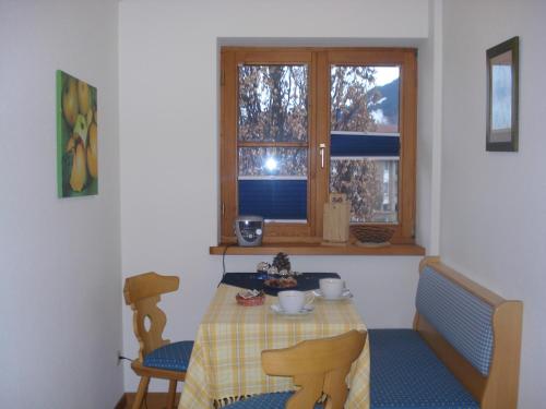 Zimmer mit einem Tisch, Stühlen und einem Fenster in der Unterkunft Landhaus Alpensee in Oberstdorf
