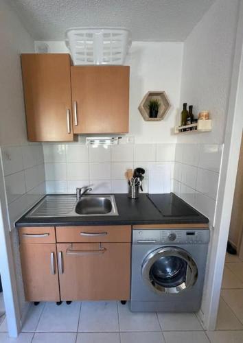 une cuisine avec un évier et une machine à laver dans l'établissement Charmant studio Port de Gruissan, à Gruissan