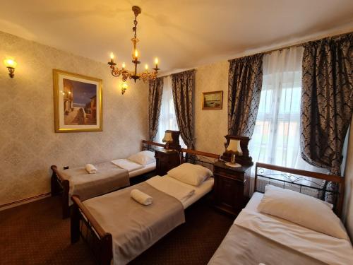 ein Hotelzimmer mit 4 Betten und einem Kronleuchter in der Unterkunft Pałac Ławica in Kłodzko