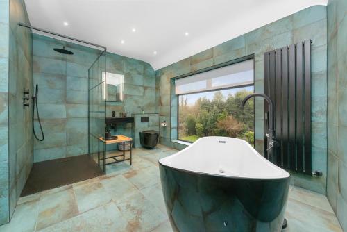 a large bathroom with a tub and a shower at Westleigh in Ashtead