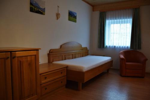 a bedroom with a bed and a chair and a window at Ferienhof Hochbrandt in Spital am Pyhrn
