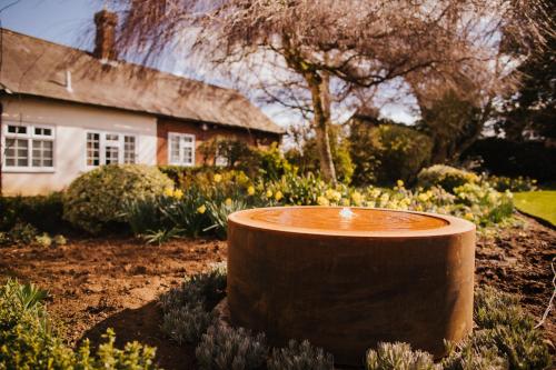 a garden with a large pot in front of a house at The Farmhouse at Redcoats in Stevenage