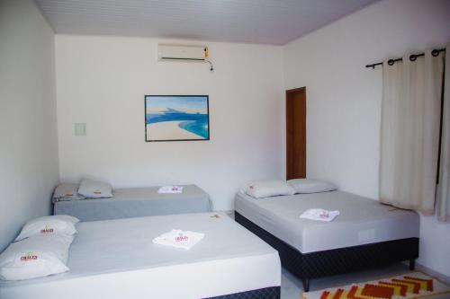 two beds in a room with white walls at Chalés Passagem do Canto in Barreirinhas