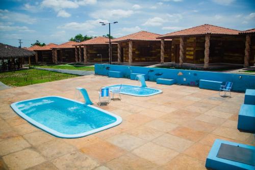 two hot tubs in a courtyard with a building at Chalés Passagem do Canto in Barreirinhas