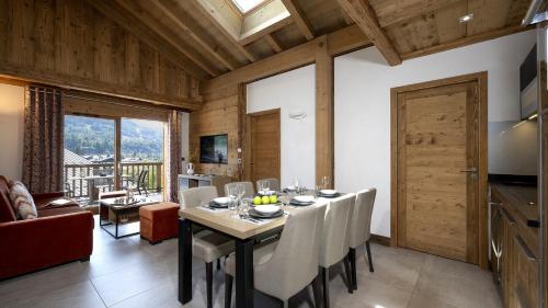 a dining room with a table and chairs and a kitchen at MGM Hôtels & Résidences - Résidence Alexane in Samoëns