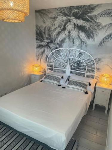 une chambre avec un grand lit blanc avec une fresque de palmiers dans l'établissement Appart Frontignan sur la plage, piscine, wifi, tv, Netflix, à Frontignan