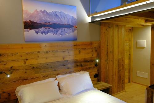 een slaapkamer met een houten accentmuur en een bed bij Arlette Chambres d'Hôtes in Aosta