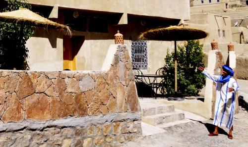 a woman standing in front of a stone building at Chateau Imilchil in Imilchil