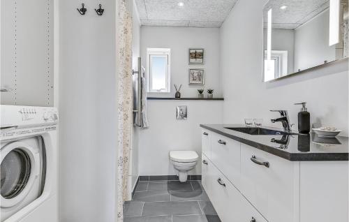 Baño blanco con aseo y lavamanos en Gorgeous Home In Faaborg With Kitchen, en Bøjden