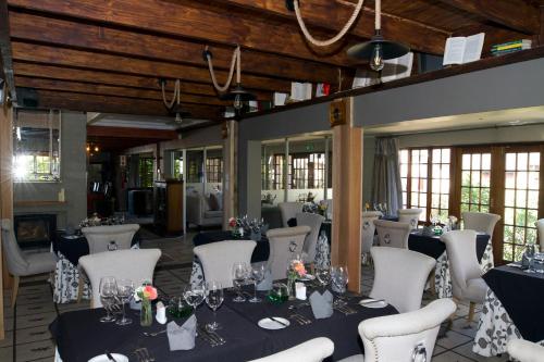 un salón de banquetes con mesas y sillas blancas en The Highlander Hotel Dullstroom, en Dullstroom