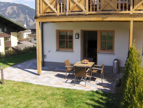 eine Terrasse mit einem Tisch und Stühlen vor einem Haus in der Unterkunft AvenidA Residenz an der Burg by Alpin Rentals in Kaprun