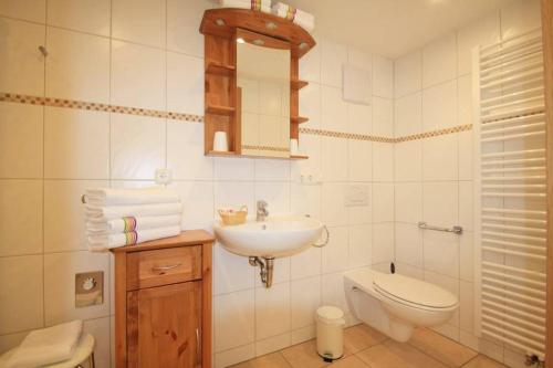 a white bathroom with a sink and a toilet at Ferienwohnungen Bergerhof in Sachrang