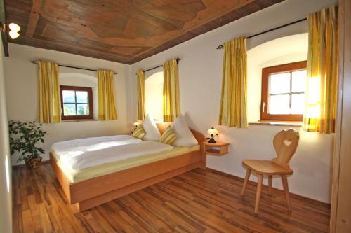 um quarto com uma cama e uma cadeira em Ferienwohnungen Bergerhof em Sachrang